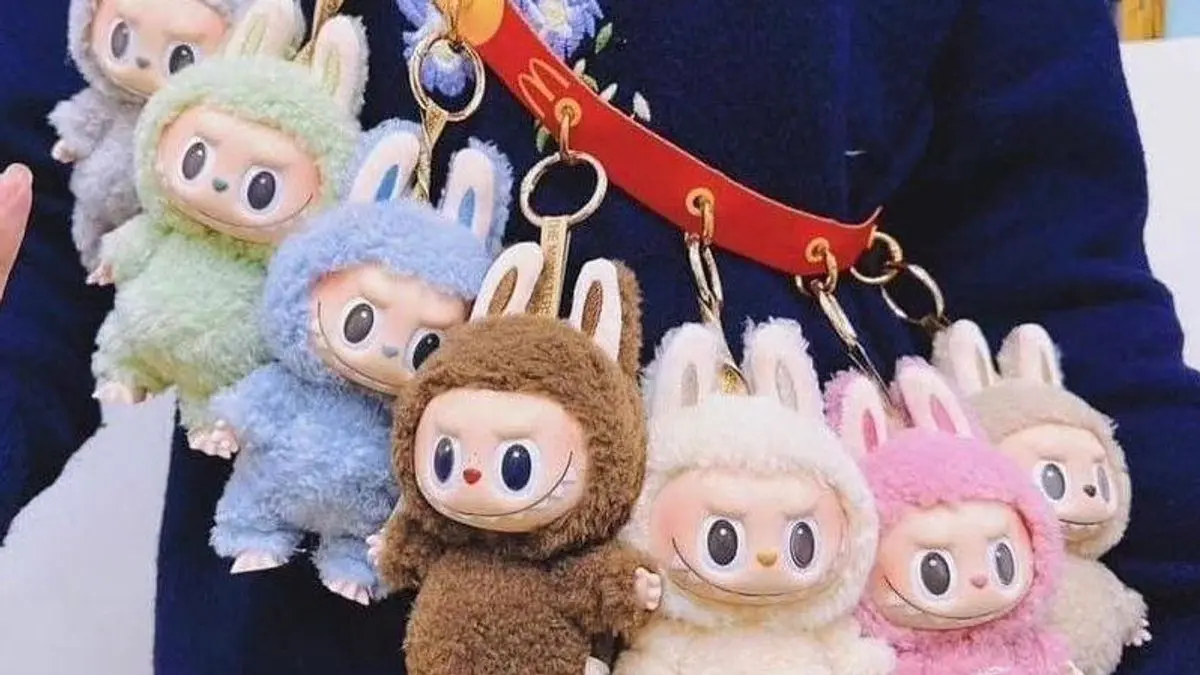 Multiple colorful Labubu plush keychains hanging on a red strap, worn across the shoulder.