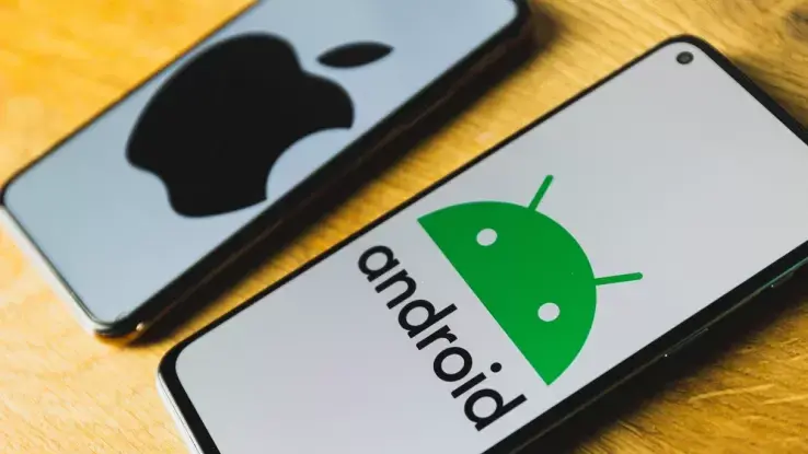 Two smartphones on a table—one showing the Android logo, the other the Apple logo—illustrating a comparison between iOS and Android security.