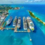Aerial view of Nassau cruise port in the Bahamas with multiple docked ships, turquoise water, and nearby Paradise Island on a sunny day.