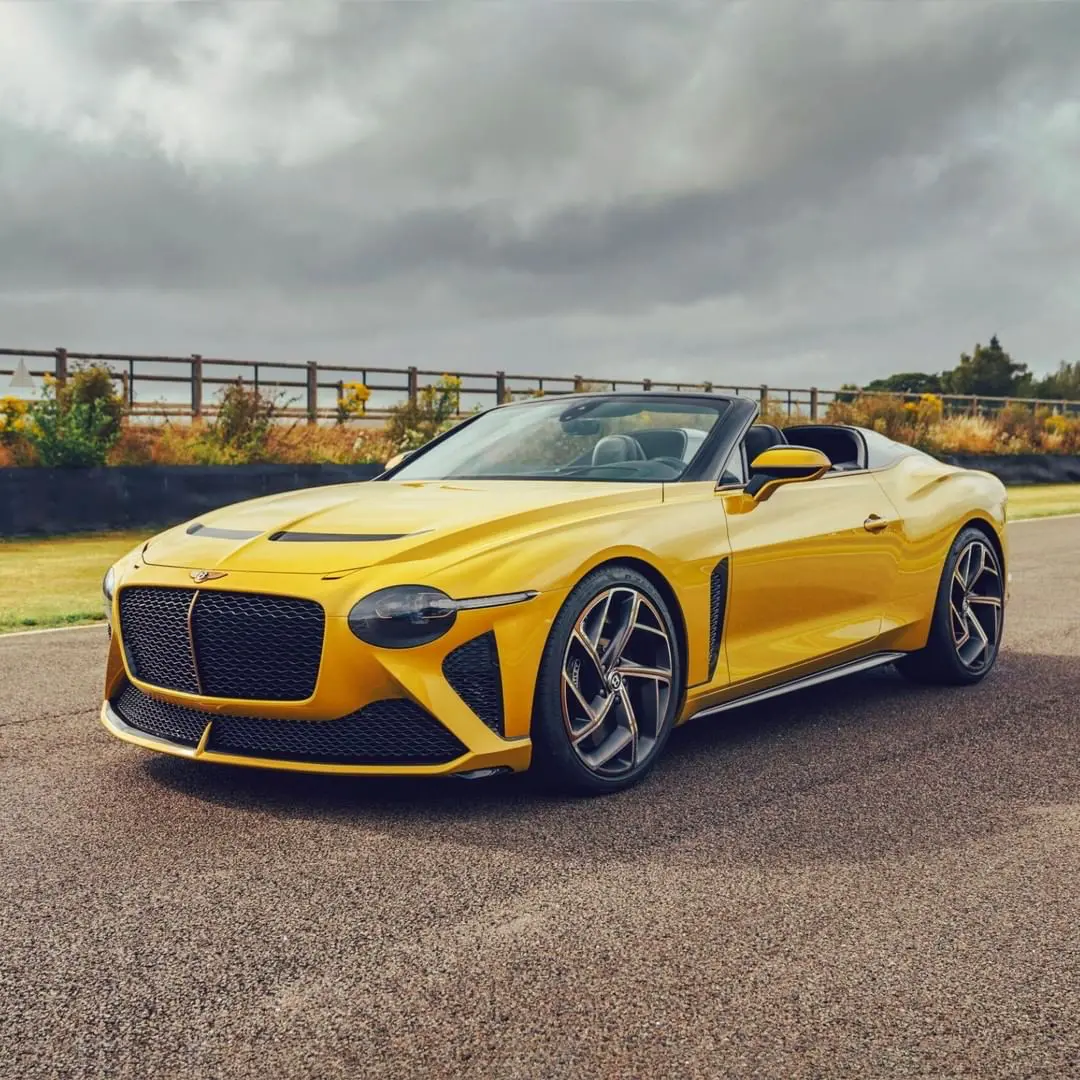 Bright yellow Bentley Mulliner Bacalar convertible on a racetrack, showcasing its sleek, roofless design and luxury craftsmanship; one of only 12 ever built.