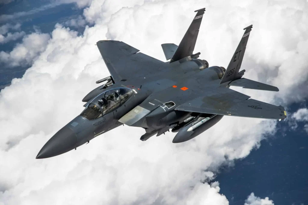 Modern Boeing F-15EX Eagle II fighter jet flying above the clouds during a high-altitude mission – showcasing its twin engines and weapon loadout.