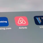 Three mobile app icons for Booking.com, Airbnb, and Vrbo are displayed side by side on a smartphone screen.