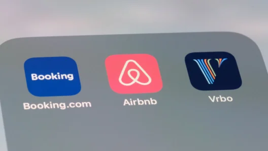 Three mobile app icons for Booking.com, Airbnb, and Vrbo are displayed side by side on a smartphone screen.