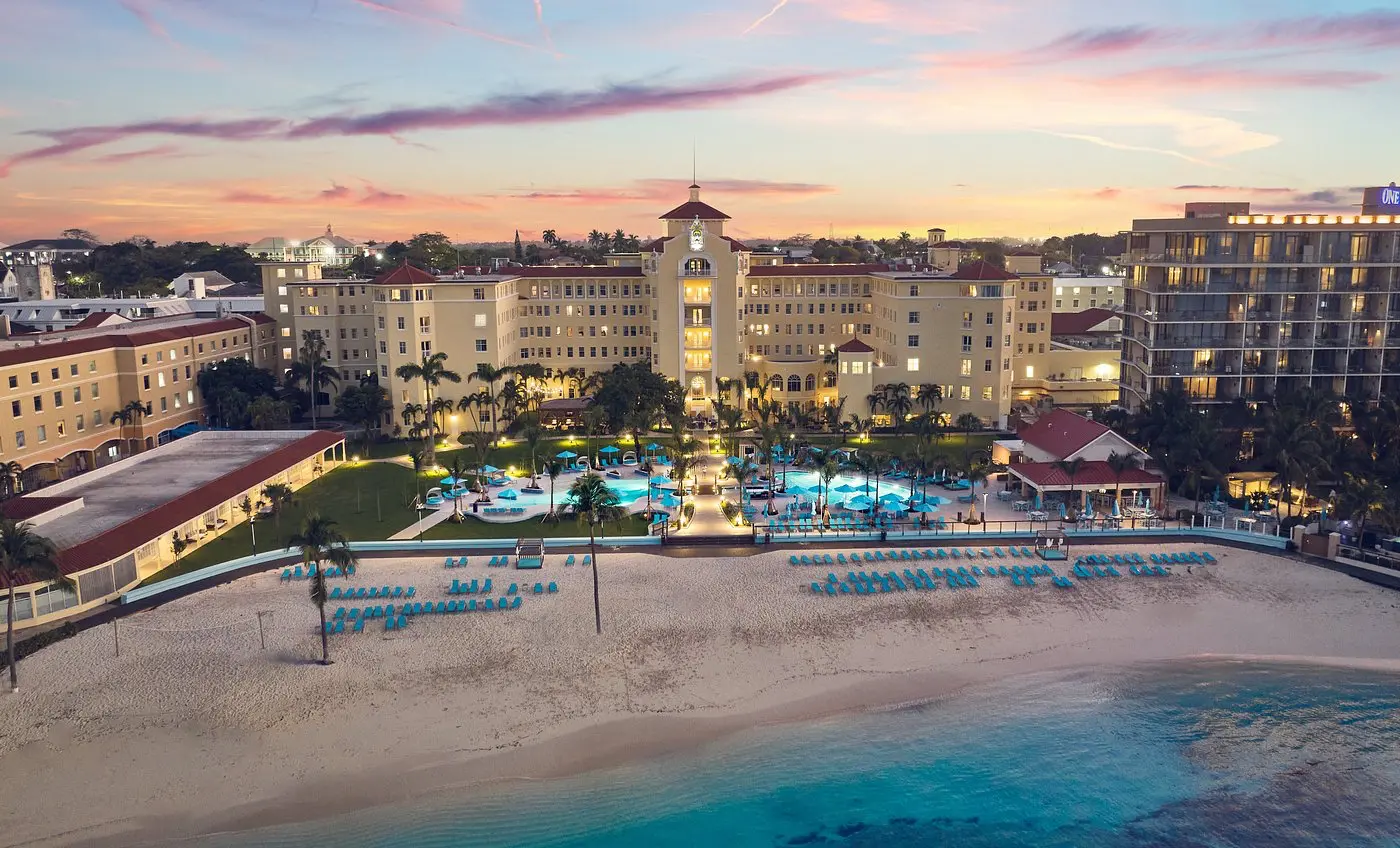 Sunset view of the historic British Colonial Hotel in Nassau, Bahamas, with beachfront access and glowing pool area.