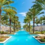 Elegant pool canal lined with palm trees and private cabanas at Grand Hyatt Baha Mar, leading toward the ocean.