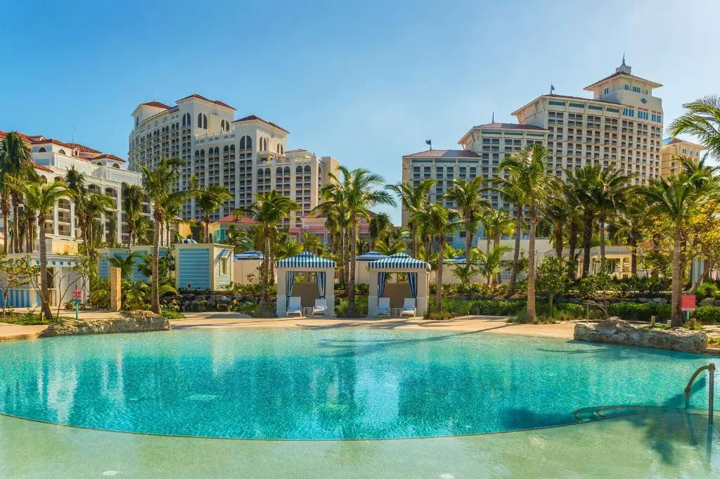 Panoramic view of Grand Hyatt Baha Mar’s main pool area with palm trees and the hotel towers in the background.