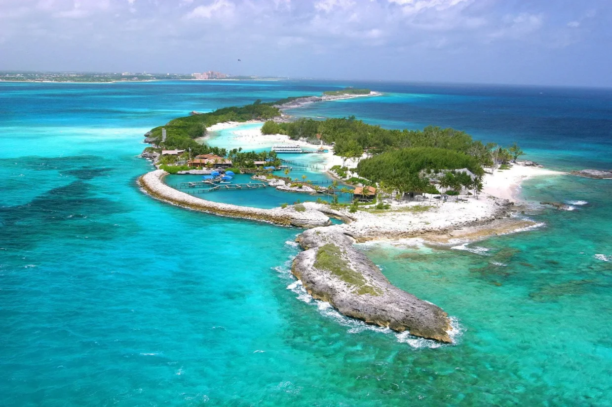 Scenic aerial view of Blue Lagoon Island surrounded by vibrant blue sea and white sandy beaches near Nassau, Bahamas.