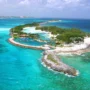 Scenic aerial view of Blue Lagoon Island surrounded by vibrant blue sea and white sandy beaches near Nassau, Bahamas.