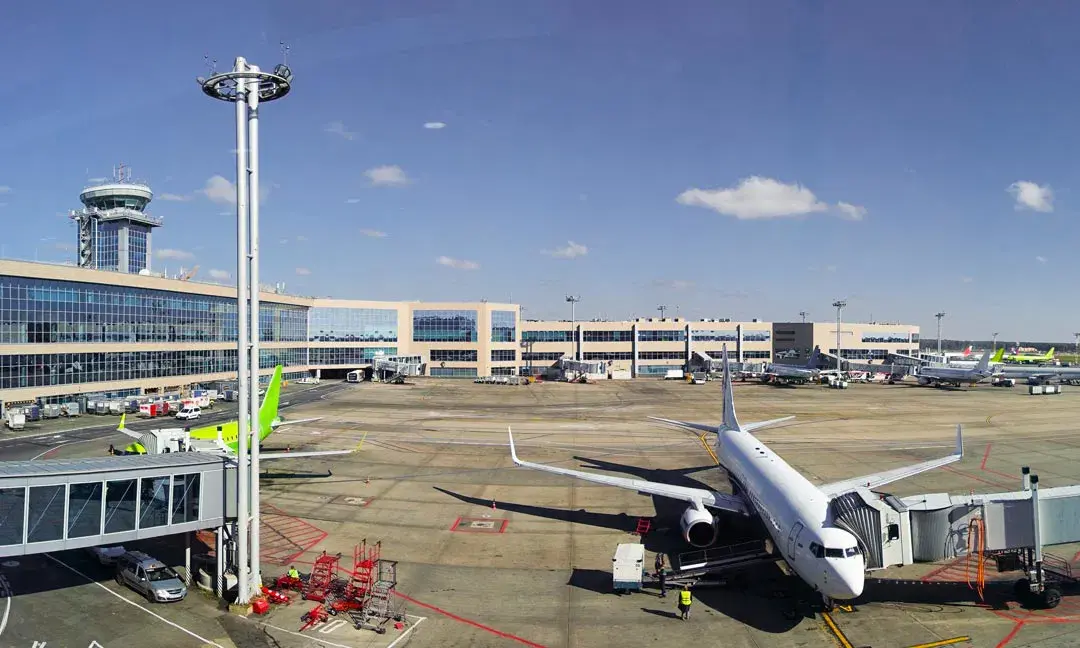 Commercial airplanes parked at the gate at Praia Airport (RAI) in Cape Verde, with the terminal building and control tower visible under a clear blue sky.