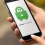 Person holding a smartphone displaying the Private Internet Access VPN app with its green padlock mascot on the screen.