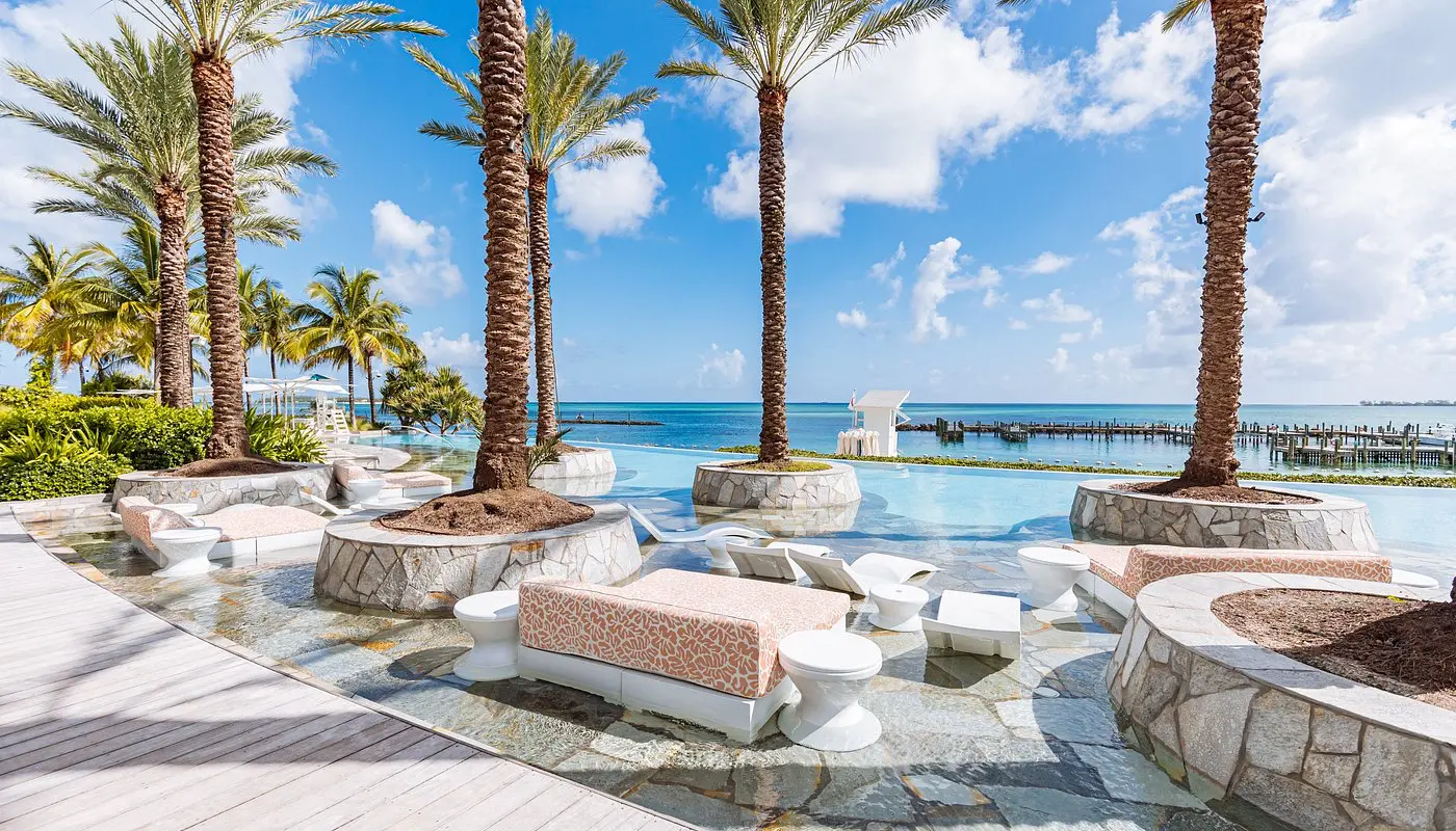 Stylish lounge and palm-fringed infinity pool at SLS Baha Mar in Nassau, overlooking the Caribbean Sea.