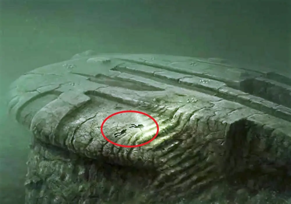 Two divers explore the mysterious Baltic Sea anomaly, a large underwater formation with unusual ridges and shapes, often speculated to be a natural or man-made structure.