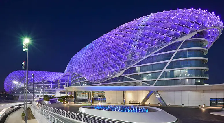 Night view of W Abu Dhabi hotel on Yas Island illuminated in purple, near the F1 race track.