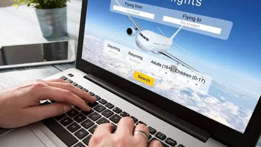 Person searching for flights online on a laptop, with a flight booking website open and hands typing on the keyboard, planning a trip and looking for the best ticket deals.