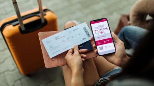 Woman at the airport holding a boarding pass, passport, and phone with a digital flight ticket from New York (JFK) to London (LHR), ready to travel with a suitcase in the background.