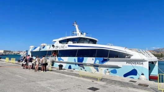 A group of travelers boarding a modern TP Line ferry named Proversa at the dock in Split, Croatia, under a bright blue sky, ready for a trip to Hvar.