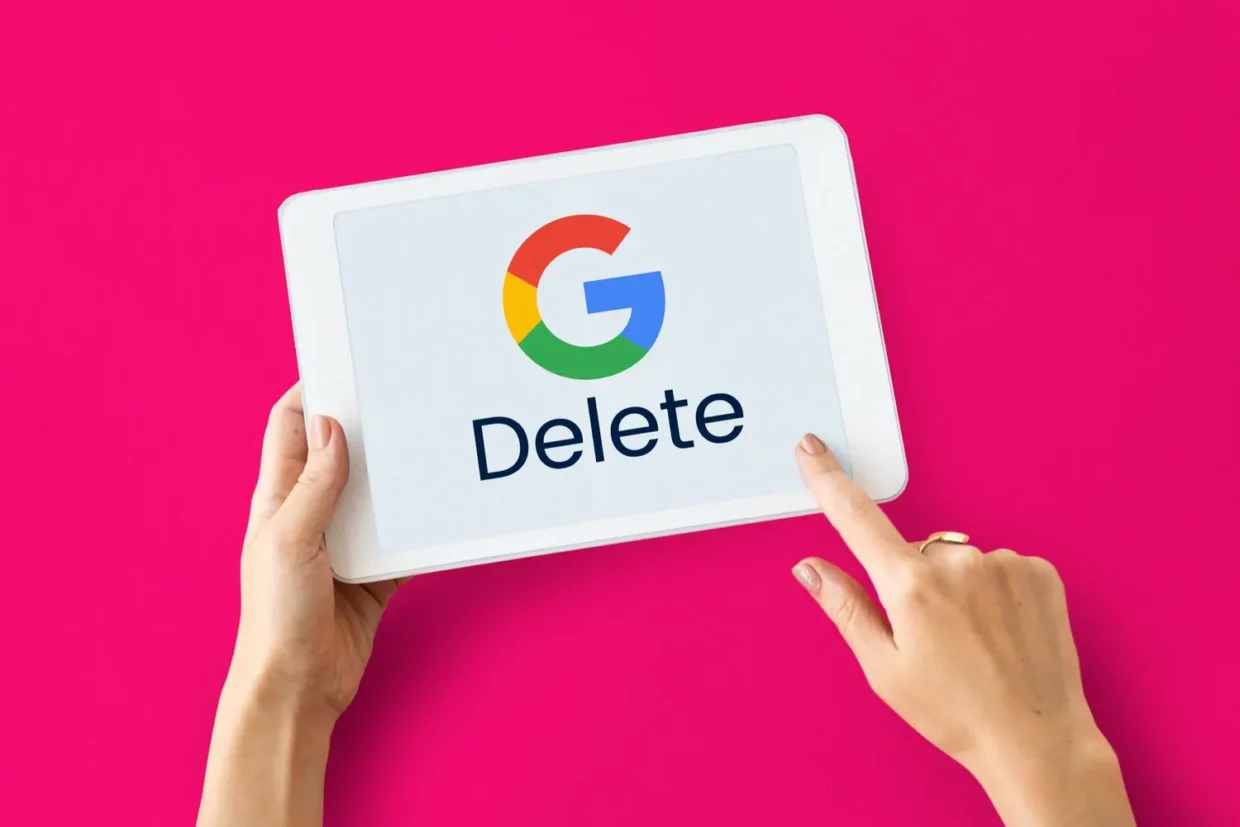 A colorful illustration showing hands holding a tablet with the Google logo and the word “Delete” on the screen, placed against a vibrant pink background – symbolizing the removal of personal data from Google.