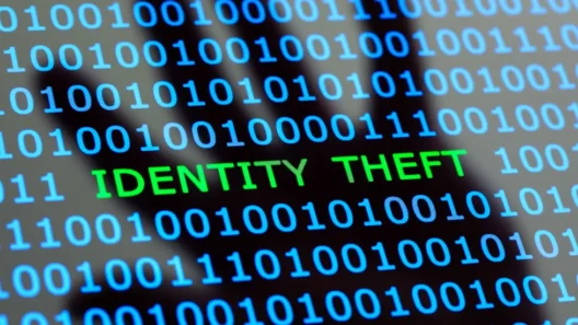 Binary code with the words "IDENTITY THEFT" highlighted, symbolizing digital data breaches and online identity theft. A shadowy human figure in the background represents cybercrime threats.