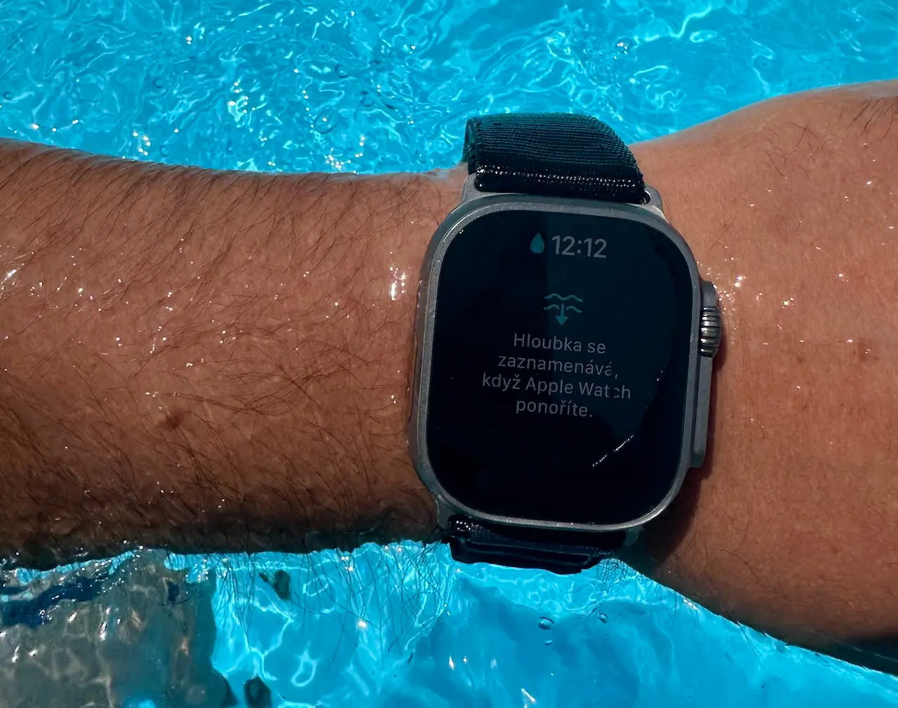 Apple Watch Ultra submerged in pool water, showing depth measurement screen at 12:12.