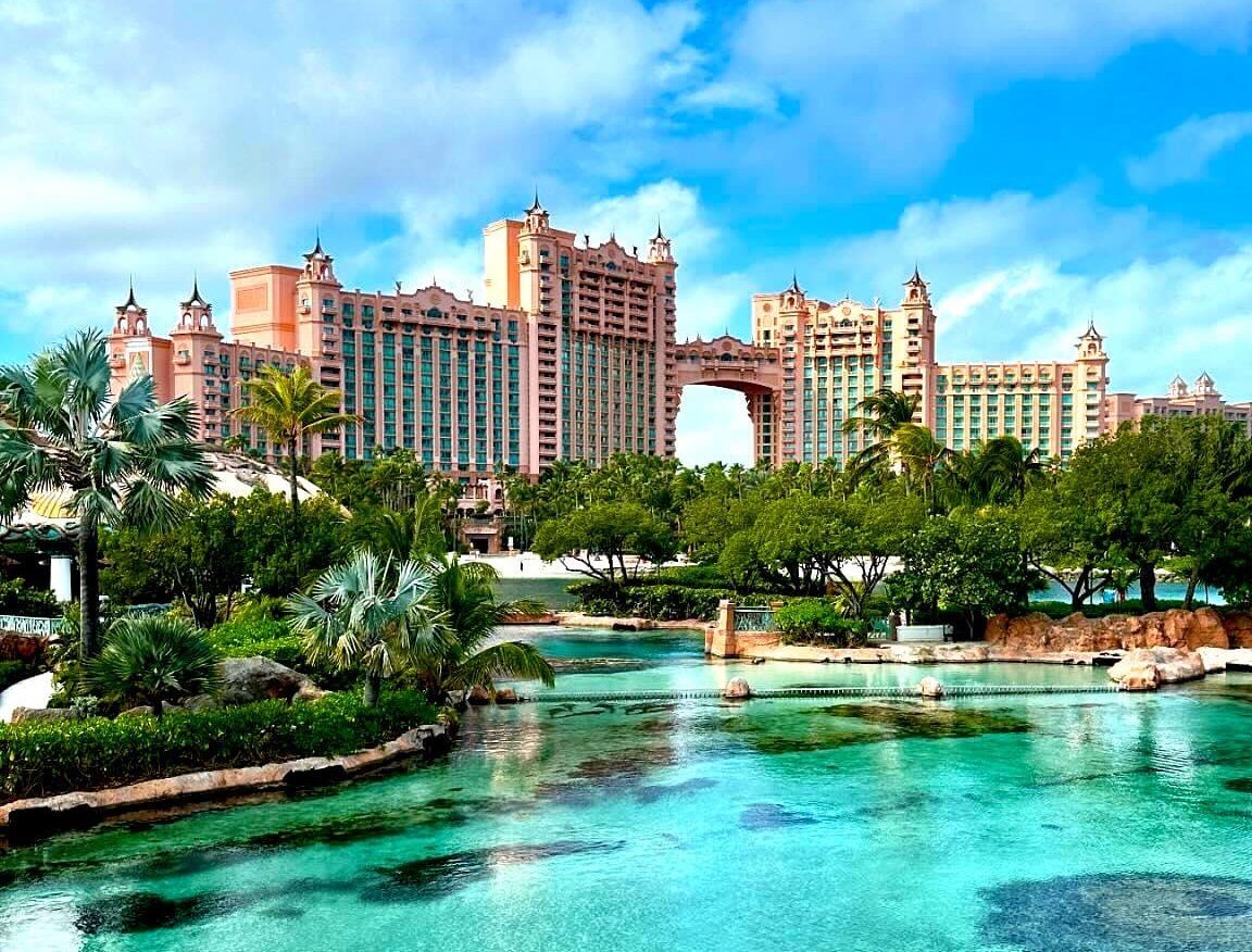 Atlantis Paradise Island resort with turquoise lagoon, lush palm trees, and tropical gardens in the Bahamas under a bright blue sky.