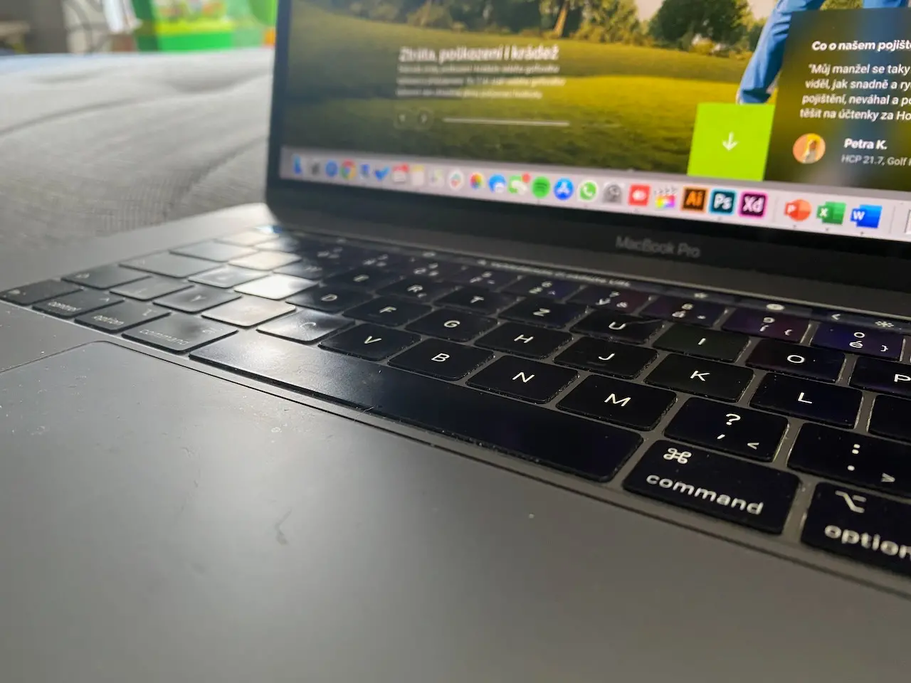 Side view of a MacBook Pro keyboard and screen with creative apps open in the dock.