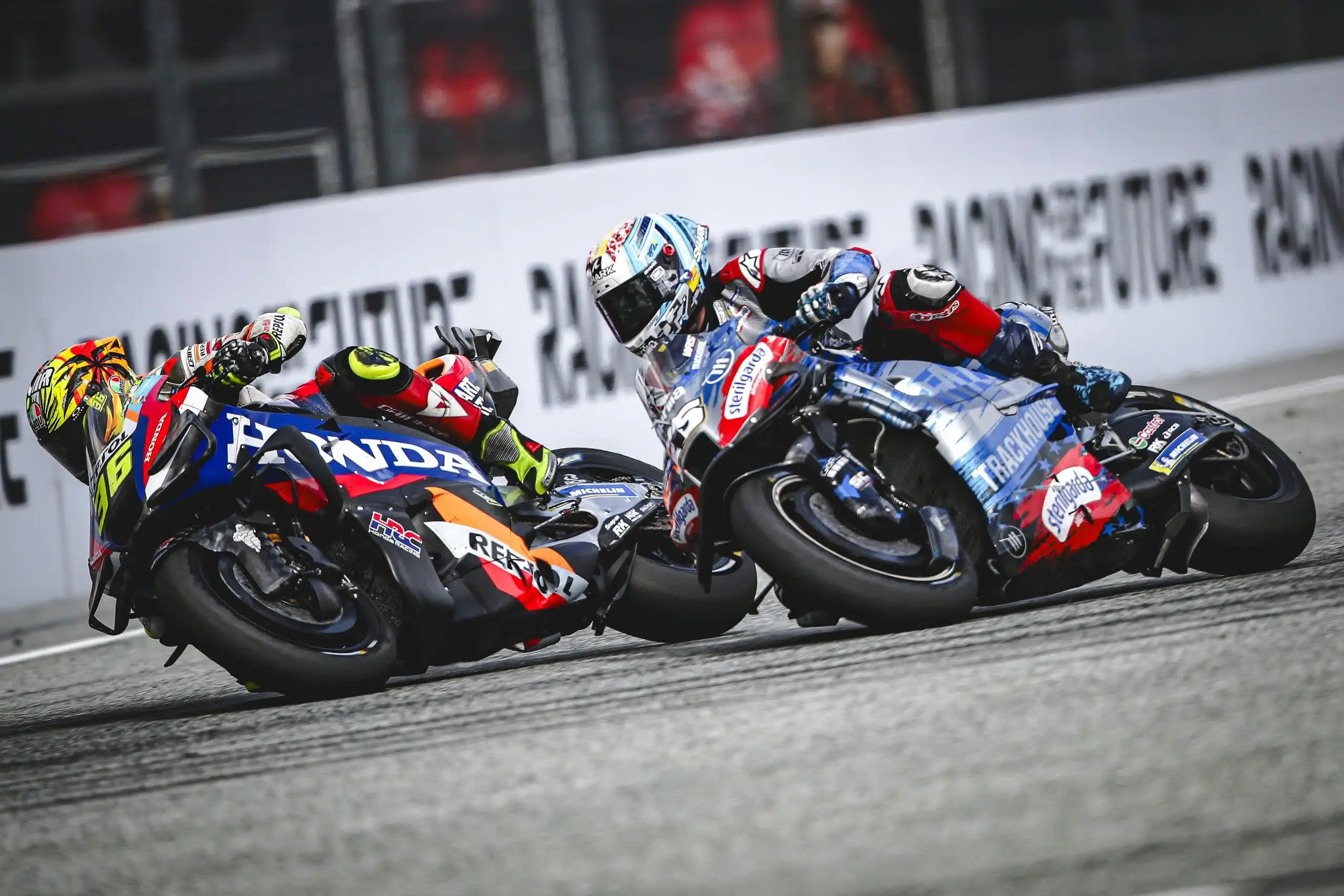 Close-up action shot of two MotoGP riders in a tight battle at the Red Bull Ring during the Austrian MotoGP 2025, showing intense cornering and bike control.