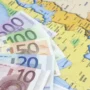 Euro banknotes on a map of Europe – illustrating salary differences and employment costs across European countries.