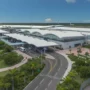 Aerial view of Lynden Pindling International Airport in Nassau, Bahamas, featuring the modern terminal, palm trees, and runway under a clear blue sky.