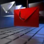 A red envelope with a phishing hook symbol hovers above a laptop keyboard, representing a phishing email attack and the risks of online scams.