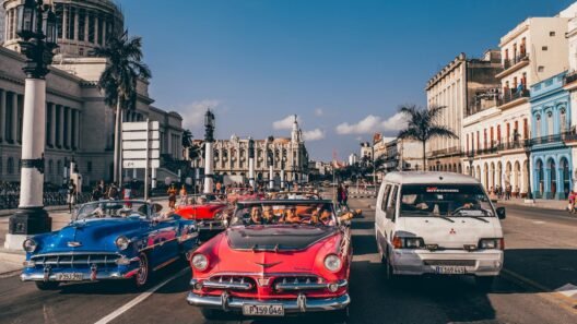 Classic vintage cars driving through the historic streets of Havana, Cuba, with colorful colonial buildings and palm trees in the background