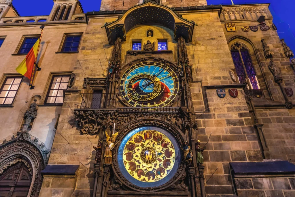 The Prague Astronomical Clock glowing at dusk in Old Town Square, its colorful astronomical dial and intricate calendar plate illuminated on the historic stone tower, capturing centuries of history and wonder.