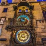 The Prague Astronomical Clock glowing at dusk in Old Town Square, its colorful astronomical dial and intricate calendar plate illuminated on the historic stone tower, capturing centuries of history and wonder.