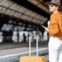 A smiling female traveler with a suitcase and coffee, ready to explore Prague using public transport.