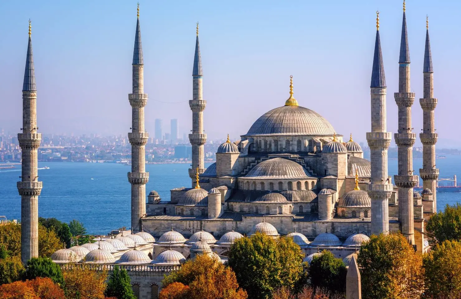 The Blue Mosque (Sultan Ahmed Mosque) in Istanbul, Turkey, with its six minarets, domes, and the Bosphorus in the background on a clear day.