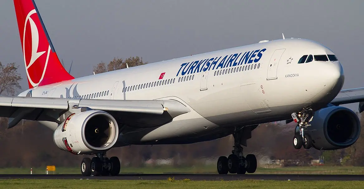 Turkish Airlines airplane preparing for takeoff on a runway, featuring the airline's logo and branding on the fuselage, with a clear view of the engines and landing gear.