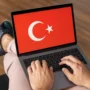 A close-up of a man’s hands typing on a laptop displaying the Turkish flag, with a soft, professional background—ideal for an article about VPNs and digital security in Turkey.