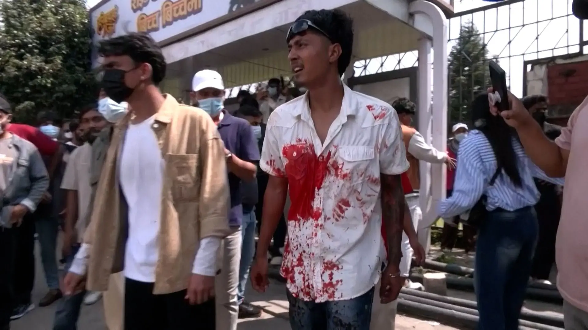 Young protester in Kathmandu with a blood-stained shirt, surrounded by demonstrators after violent clashes during Nepal’s social media ban protests in 2025.