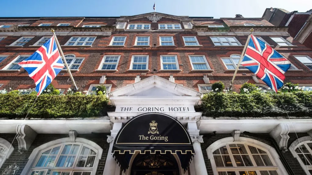 Front entrance of The Goring Hotel in London with Union Jack flags and classic red brick facade, known for hosting royals and offering true British luxury.
