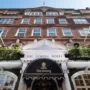 Front entrance of The Goring Hotel in London with Union Jack flags and classic red brick facade, known for hosting royals and offering true British luxury.
