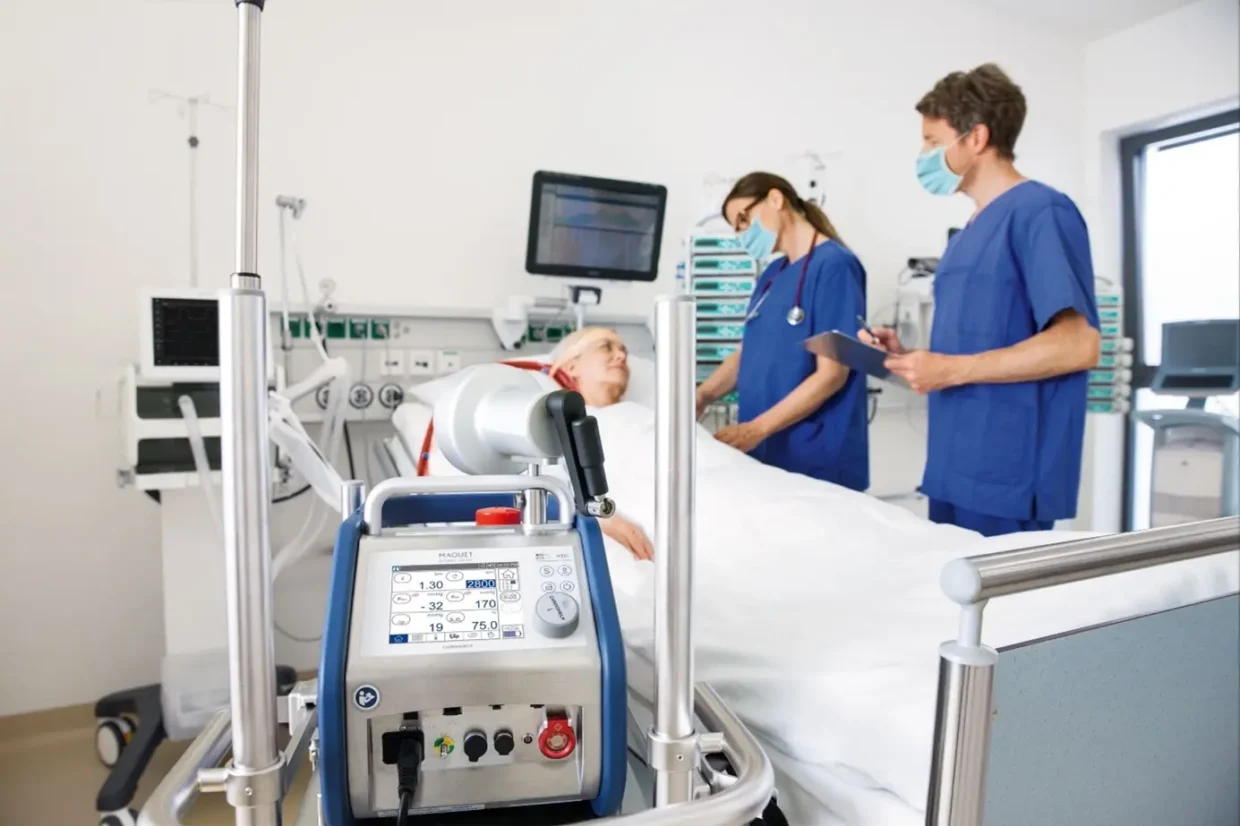 ECMO machine beside an ICU patient receiving life support while doctors monitor vital signs.