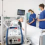 ECMO machine beside an ICU patient receiving life support while doctors monitor vital signs.