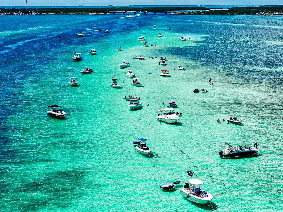 Boats anchored in the crystal-clear shallow waters off Islamorada, surrounded by vibrant turquoise shades and summer energy.