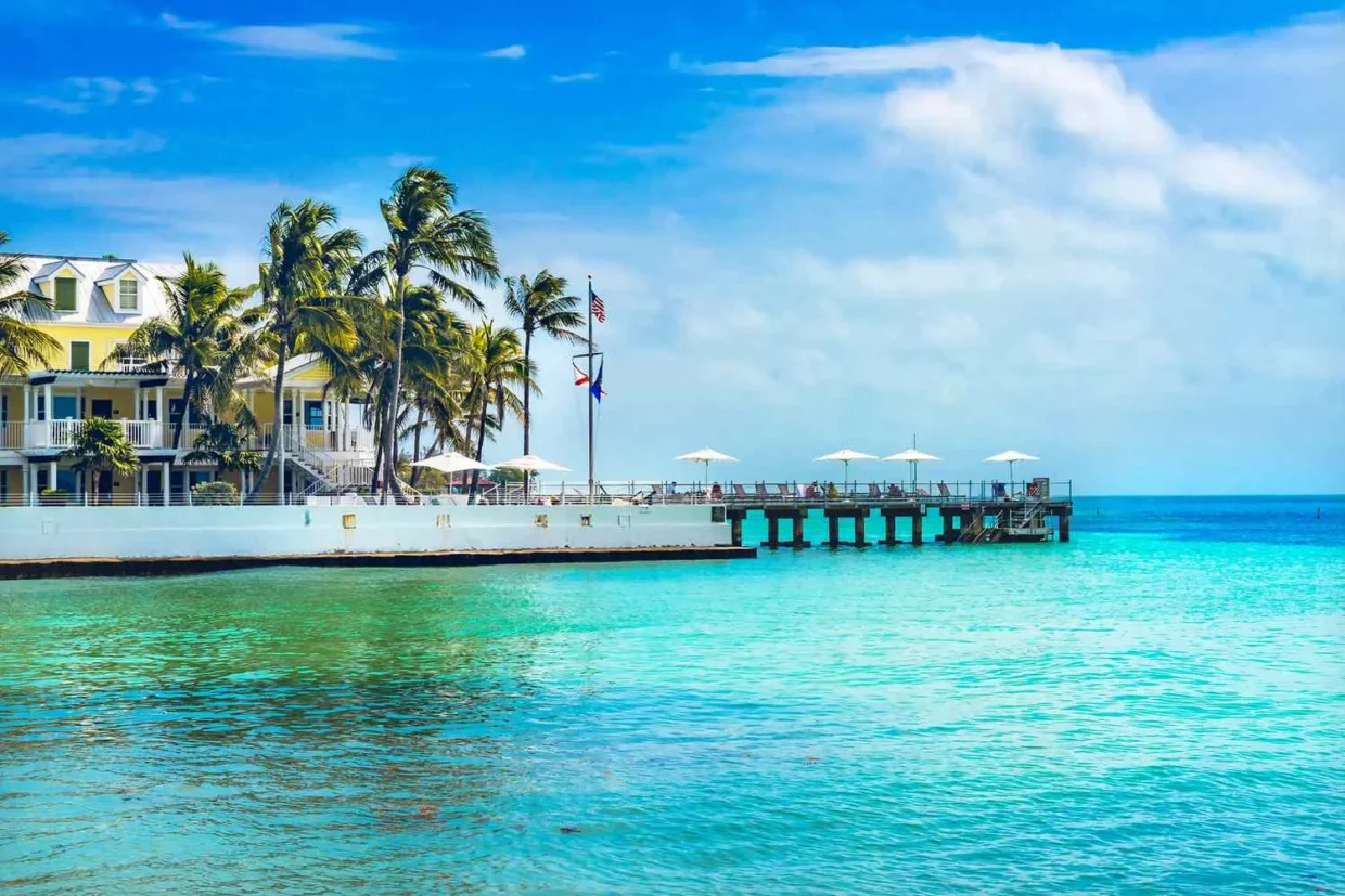 Historic white guesthouses and a palm-lined dock over turquoise water in Key West, capturing the tropical charm of the island.