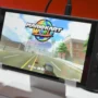 Nintendo Switch 2 running Mario Kart World in handheld mode on a bright screen, showing Mario racing down a city road.
