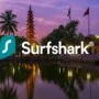 Surfshark logo centered over a panoramic view of Hanoi, Vietnam, showing city skyline, lake, and local architecture in the evening light.