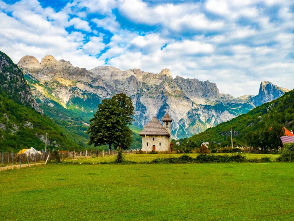Scenic view of Thethi Church in Albania with the Accursed Mountains in the background on a sunny day