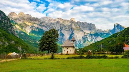 Scenic view of Thethi Church in Albania with the Accursed Mountains in the background on a sunny day