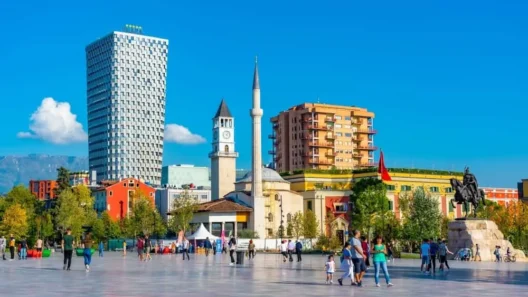 Skanderbeg Square in Tirana with the Clock Tower, Et’hem Bey Mosque, modern high-rises, and the statue of national hero Skanderbeg under a clear blue sky