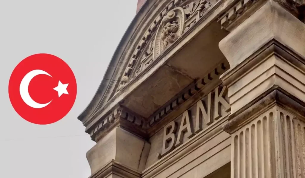 Historic stone bank building with the word "BANK" on the facade and the Turkish flag symbol overlayed, representing Turkish financial institutions.