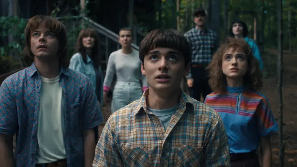 stranger-things-5-group-scene-hawkins_ads | Venclikovi.com The Stranger Things crew looking up in shock in the woods near Hawkins.